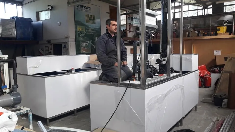 Una persona junto a un equipo acristalado en preparación dentro del taller