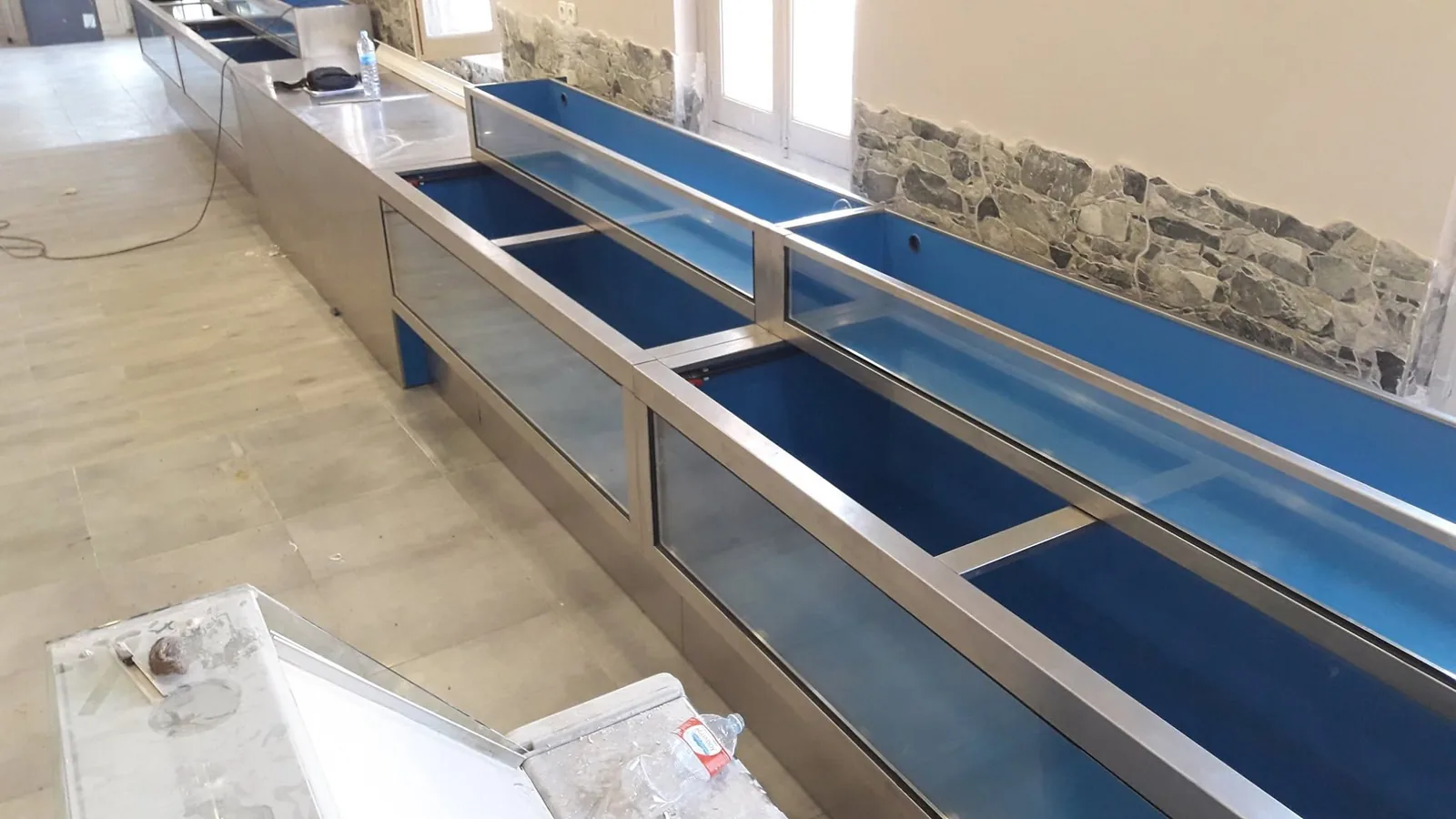 Viveros alargados de interior azul durante su montaje junto a una pared de piedra
