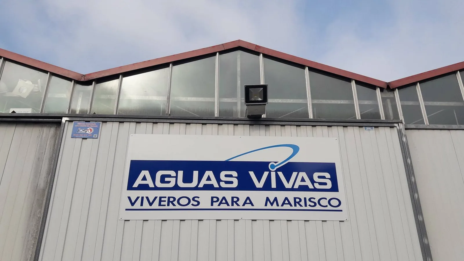 Rótulo de Aguas Vivas, viveros para marisco, en la fachada de la nave