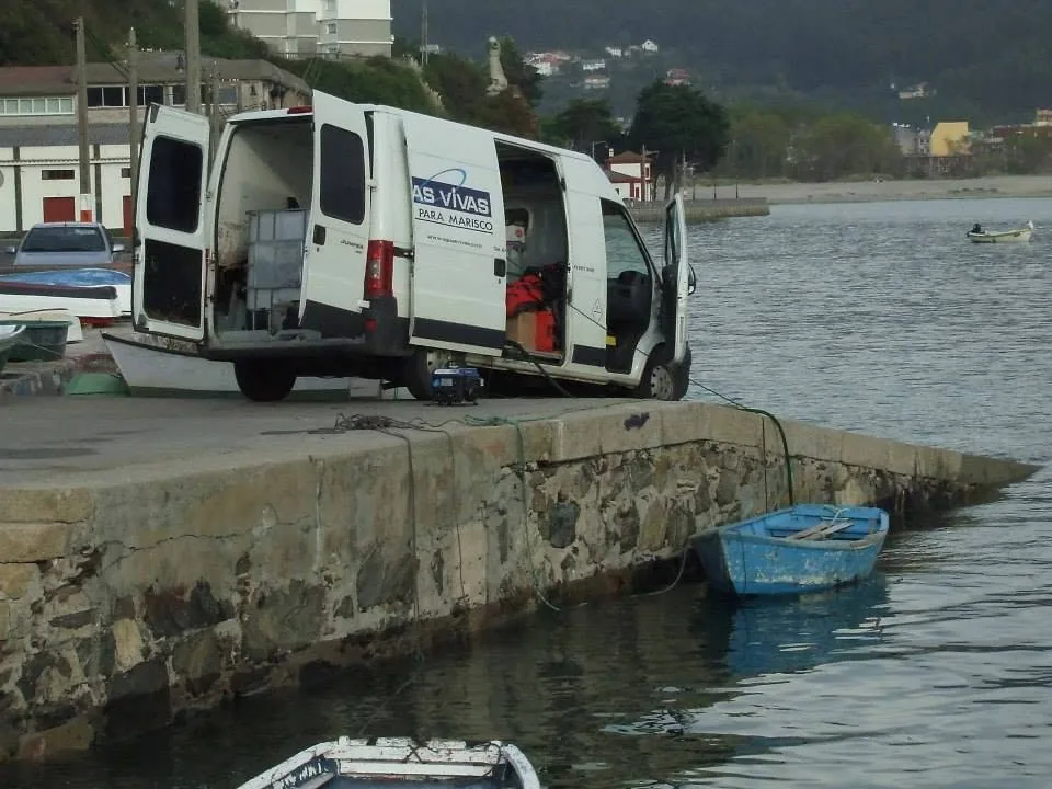 Furgoneta rotulada de Aguas Vivas con las puertas abiertas junto a un muelle
