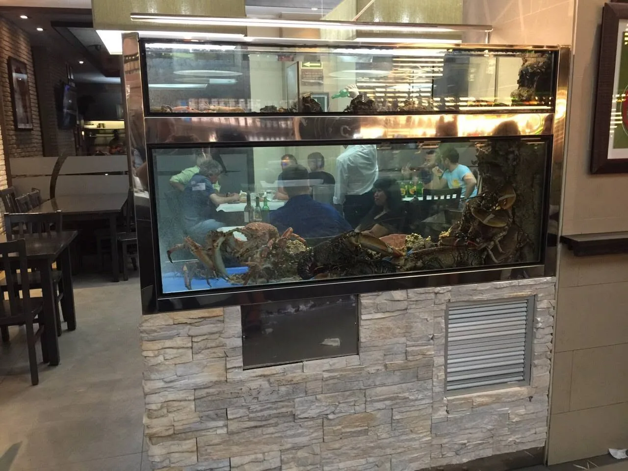 Vivero de dos niveles con crustáceos visibles en un restaurante